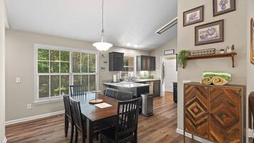 A modern kitchen with a central island, wooden dining table, and chairs.
