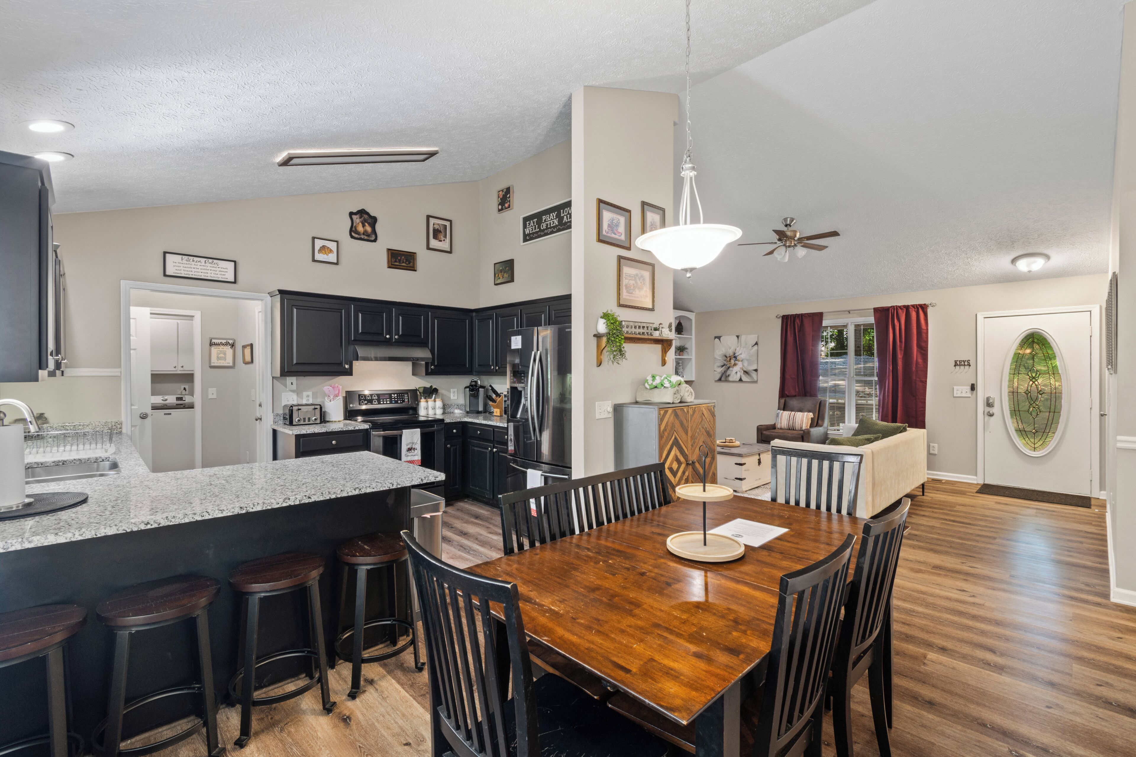 A modern kitchen with dark cabinets, a stainless steel refrigerator, and a granite countertop.