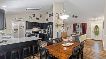 A modern kitchen with dark cabinets, a stainless steel refrigerator, and a granite countertop.