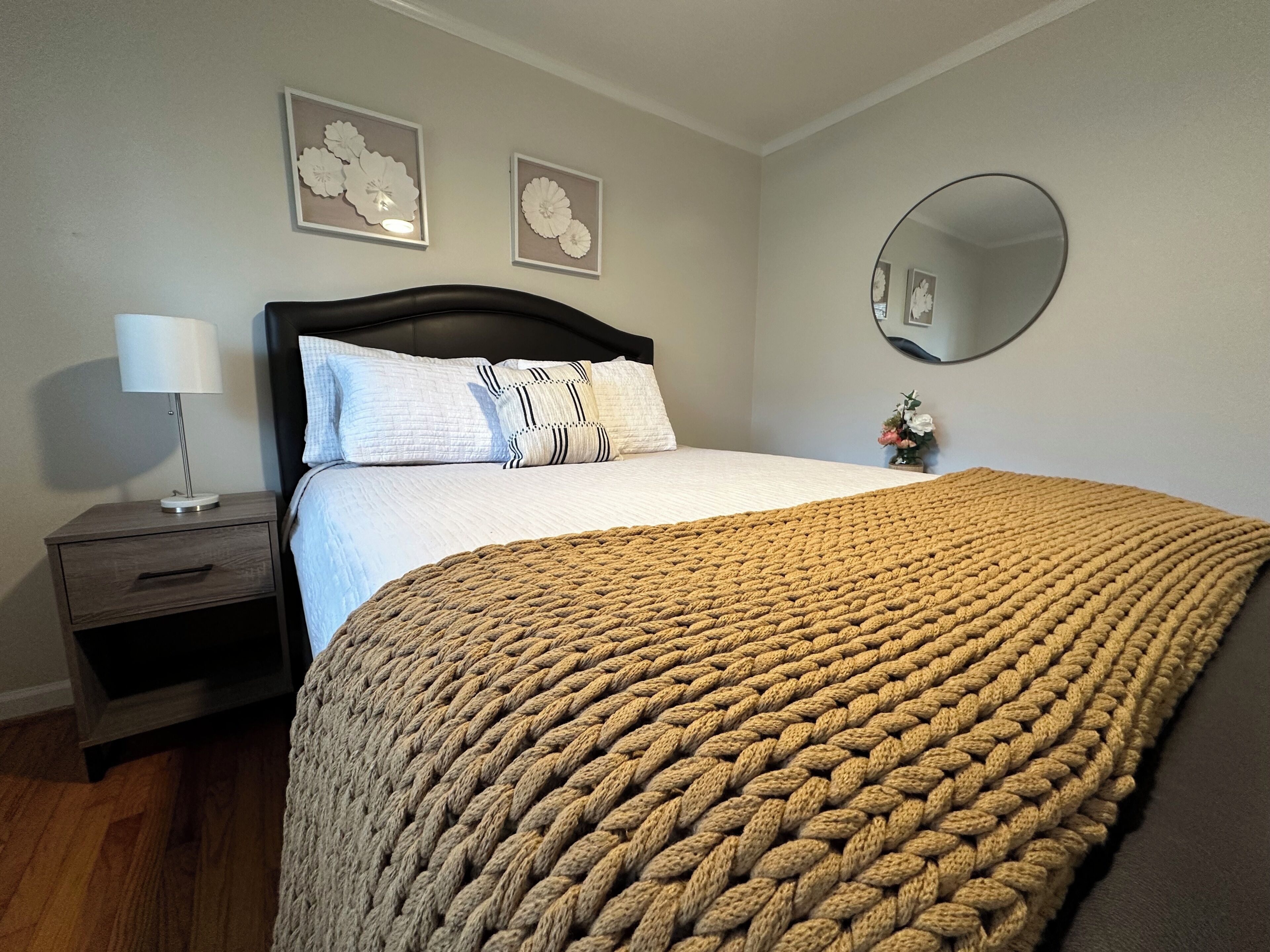 Un dormitorio con cama, mesita de noche, lámpara, espejo y decoración en la pared.