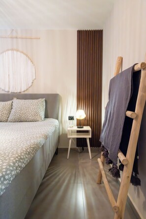 Ein Hotelzimmer mit einem Bett, einem Nachttisch, einer Lampe, einem Vorhang und einem Holzstuhl.