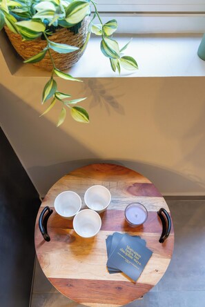 Ein runder Holztisch mit drei weißen Schalen, einer Kerze und einem Buch mit dem Titel 'Motivation verfliegt, Disziplin bleibt.'