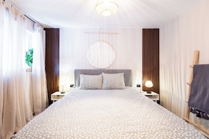 A hotel room with a large bed, two bedside tables, a round wall hanging, and curtains. - Stylish Apartment l Patio l 3 min to Mambo Beach (Willemstad)