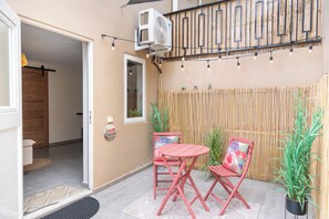An outdoor patio area with a table and chairs, a bamboo fence, and a welcome sign. - Stylish Apartment l Patio l 3 min to Mambo Beach (Willemstad)