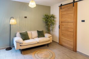 A room with a sofa, a sliding door, a floor lamp, and a potted plant. - Stylish Apartment l Patio l 3 min to Mambo Beach (Willemstad)