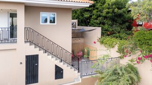 Ein mehrstöckiges Wohngebäude mit Treppe, Sitzbereich im Freien und Grünflächen.