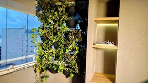 A room with a large window, a wall-mounted plant, and a shelf with a sign. - Loft no Studio Unique com Garagem 1104 (Belem)