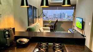 A modern kitchen with a gas stove, a coffee machine, and a dining area with a table and chairs. - Loft no Studio Unique com Garagem 1104 (Belem)
