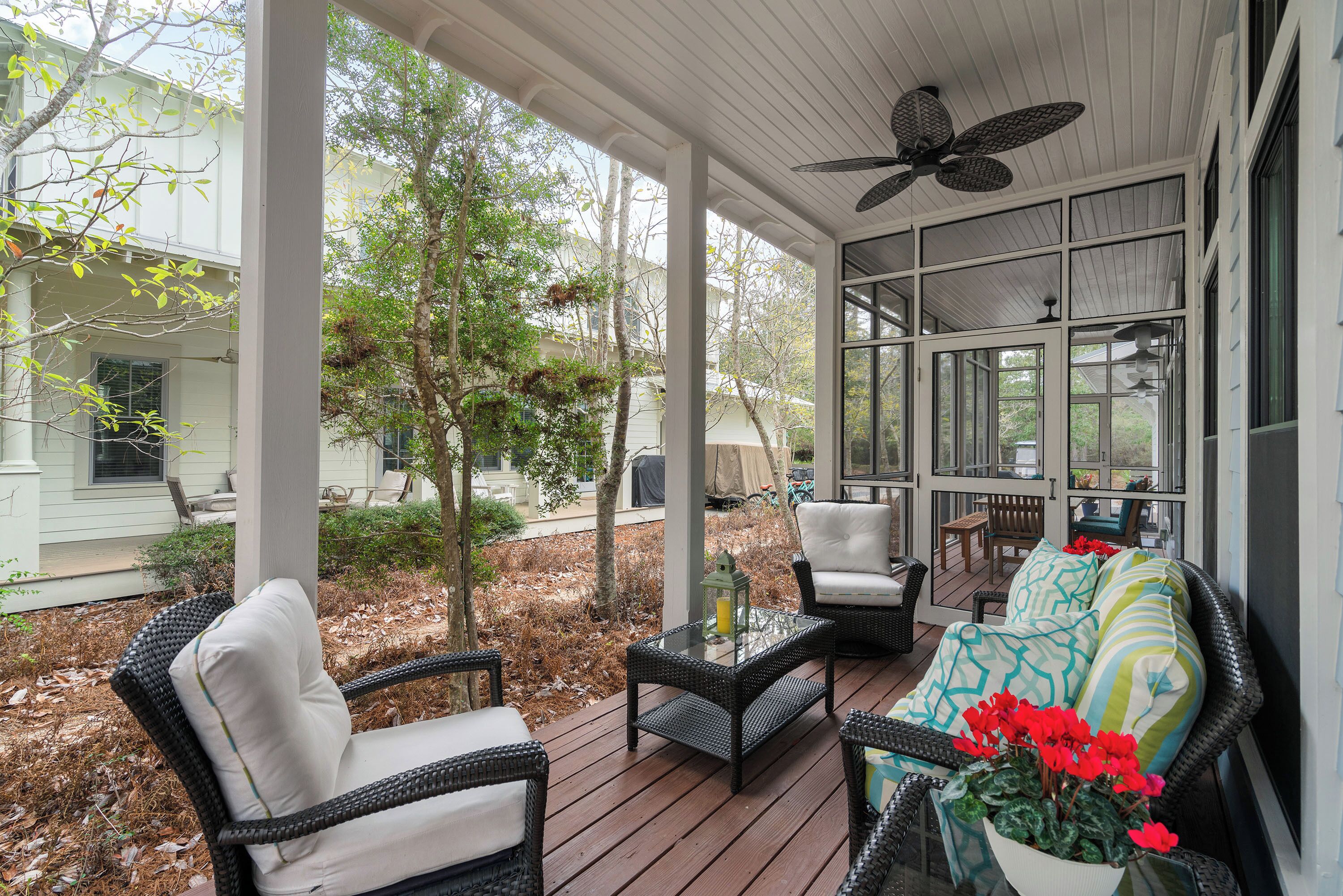 A covered porch with wicker furniture, a ceiling fan, and a view of the surrounding area.