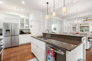 A modern kitchen with a stainless steel refrigerator, granite countertops, and a central island with a sink. - Chic WaterColor Getaway with 4 Suites Near Seaside and 30A. Bikes and Wraparound (Santa Rosa Beach)