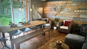 Un intérieur chaleureux avec une table à manger en bois, des chaises, un canapé et une cheminée.
