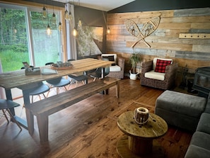 A cozy interior with a wooden dining table, chairs, a sofa, and a fireplace.