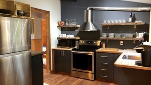 Une cuisine moderne dotée d’appareils électroménagers en acier inoxydable, de planchers en bois et d’étagères intégrées.