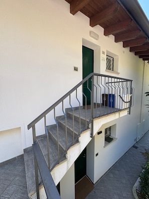 Eine Treppe mit Metallgeländer führt zu einer grünen Tür.