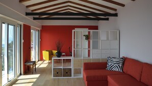 Un salon moderne avec un mur d’accent rouge, une étagère blanche, un canapé rouge et un fauteuil jaune.