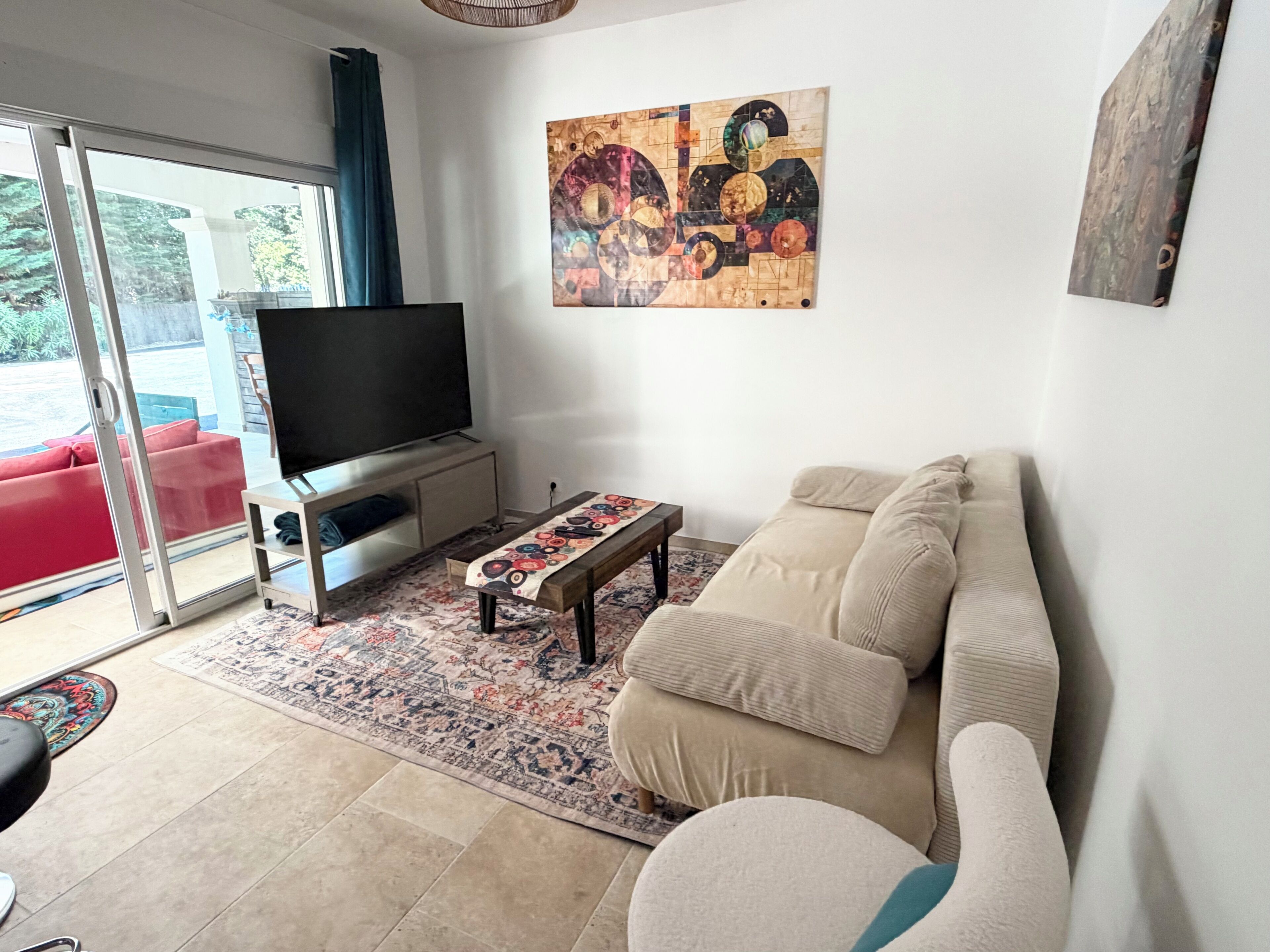 A living room with a sofa, a coffee table, a flat-screen TV, and a patterned rug.