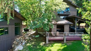 Une maison moderne dotée d’une terrasse, d’un espace salon extérieur abrité et d’un grand arbre qui offre de l’ombre.