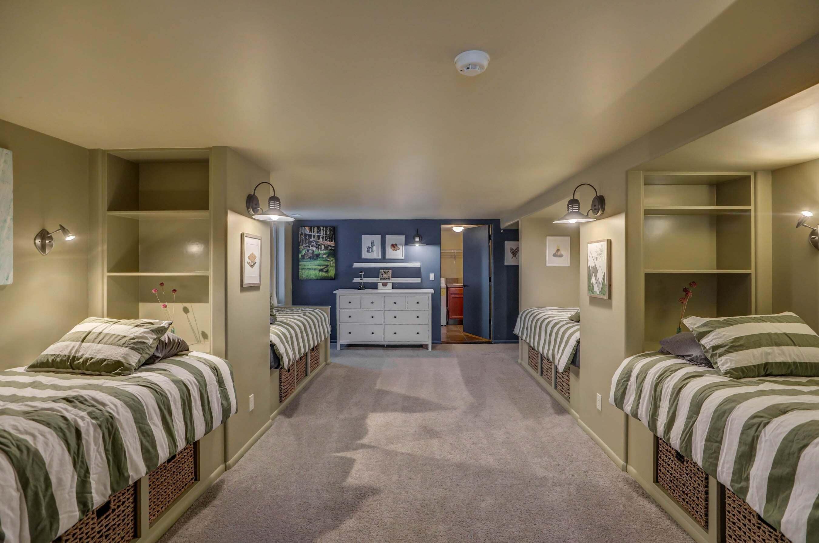 A bedroom with two beds, a dresser, and a hallway leading to a bathroom.