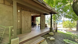 Une terrasse en bois avec des sièges extérieurs, un espace couvert avec un bar et une vue sur l’extérieur.