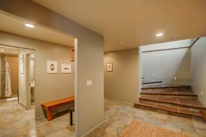 Un couloir avec un banc, un escalier et des tableaux encadrés accrochés aux murs.