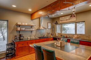 Une cuisine spacieuse dotée d’un grand îlot central, de meubles en bois et d’un luminaire suspendu moderne.
