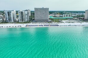 Een kuststadsgezicht met hoge gebouwen, een zandstrand en een heldere turquoise zee.