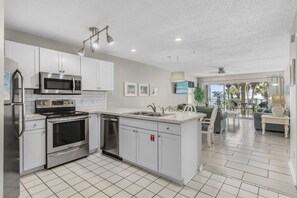 A modern kitchen with stainless steel appliances, a dishwasher, and a dining area with a view. - ☀️Maravilla 3208 | Walk 2 Beach | Free beach service | 2 Pools + Hot Tub⛱️ (Miramar Beach)