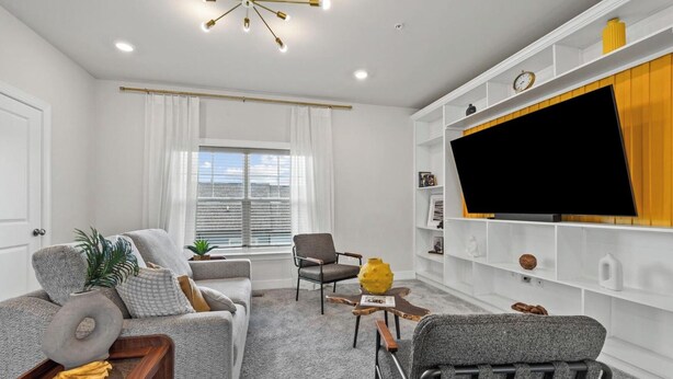 A modern living room with a sofa, armchair, and a television on a white wall. - Luxury Furnished 3BR Townhome-Walk to Rio and Crown Plaza Garage-Modern Finishes (Gaithersburg)