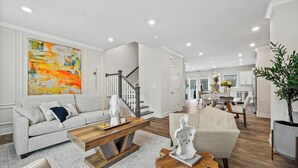 A modern living room with a sofa, coffee table, and decorative items. - Luxury Furnished 3BR Townhome-Walk to Rio and Crown Plaza Garage-Modern Finishes (Gaithersburg)