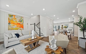 A modern living room with a sofa, coffee table, and decorative items. - Luxury Furnished 3BR Townhome-Walk to Rio and Crown Plaza Garage-Modern Finishes (Gaithersburg)
