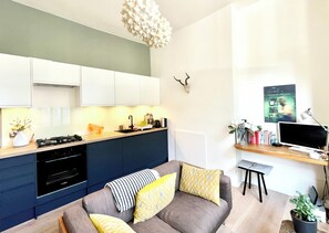 A modern kitchen with a built-in stove, white cabinets, and a hanging light fixture. - Stylish bright apartment in trendy Islington, with cafes, bars, and restaurants (London)