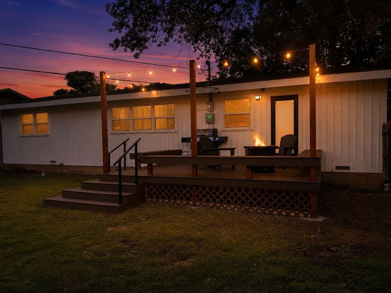 A single-story building with a deck, outdoor seating, and a barbecue grill.