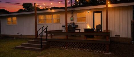A single-story building with a deck, outdoor seating, and a barbecue grill.