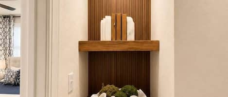 A hallway with a wooden shelf under an arched alcove, a white wall, and a door leading to another room.