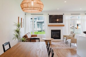 A modern living room with a fireplace, a dining table, and seating arrangements.