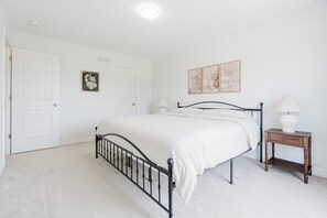 A bedroom with a bed, bedside lamps, a door, and wall art.