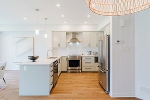 A modern kitchen with stainless steel appliances, a central island, and pendant lighting.