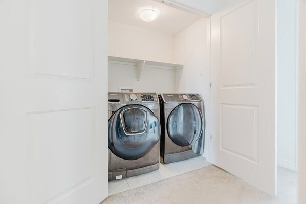 A laundry room with two front-loading washing machines and a white door.