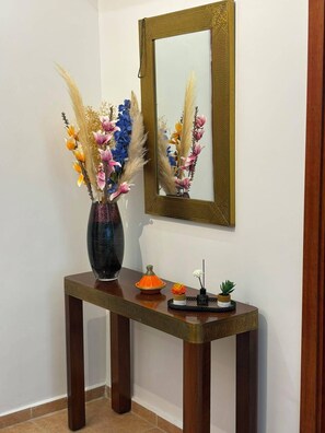Una consola de madera con un florero, un espejo y objetos decorativos.