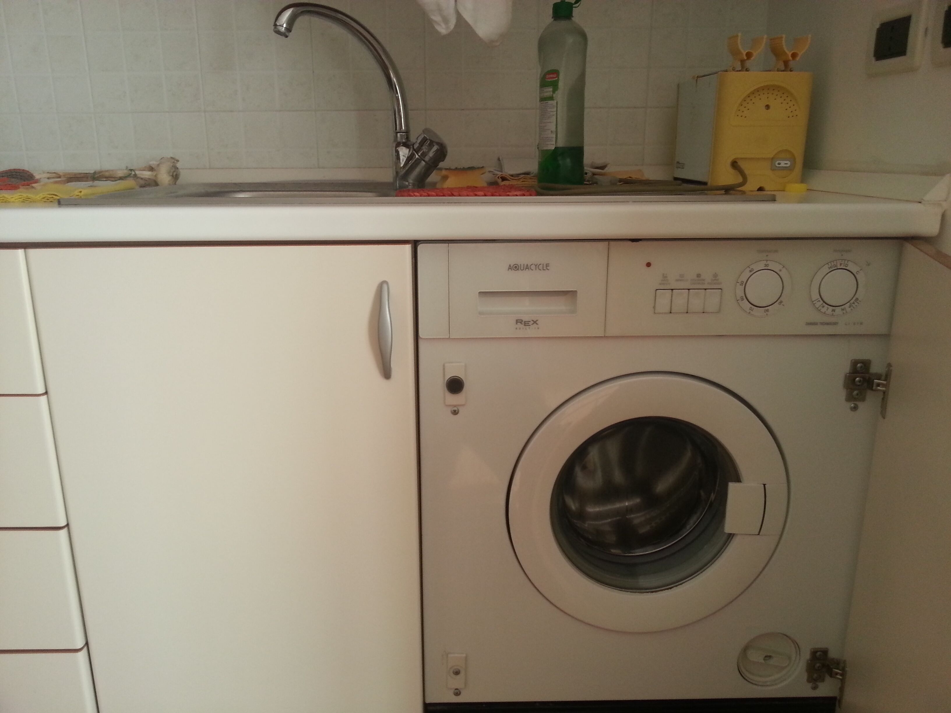 Une machine à laver compacte dotée d’un panneau de commande, d’un évier et d’un robinet.