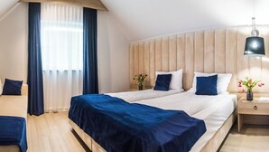 Une chambre d’hôtel avec un lit, un canapé, une télévision et une table de chevet avec une lampe.