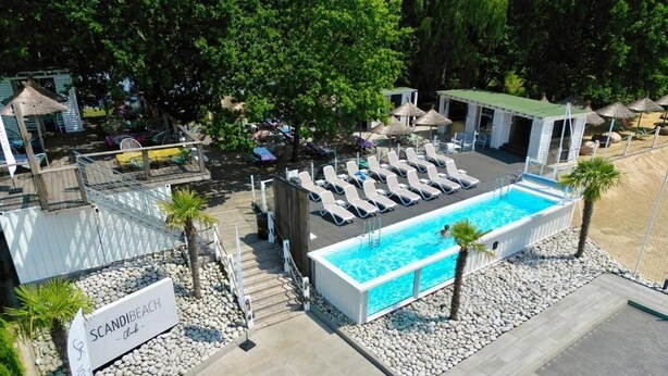 Un espace piscine avec des chaises longues et un panneau indiquant « Scandibach Club ».
