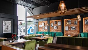 Un restaurant avec des banquettes et des tables, des murs en briques et des lampes suspendues.