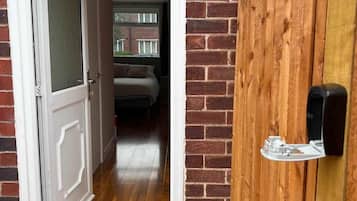 A doorway leading to a room with a bed and a window, a wooden fence, and a welcome mat with 'YAY!' on it.