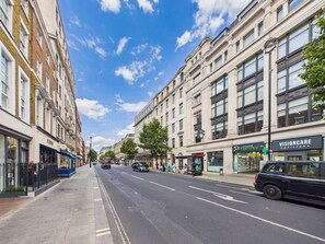 A city street with buildings, shops, and a clear sky. - Chic Baker Street Apartment with Balcony (Greater London)