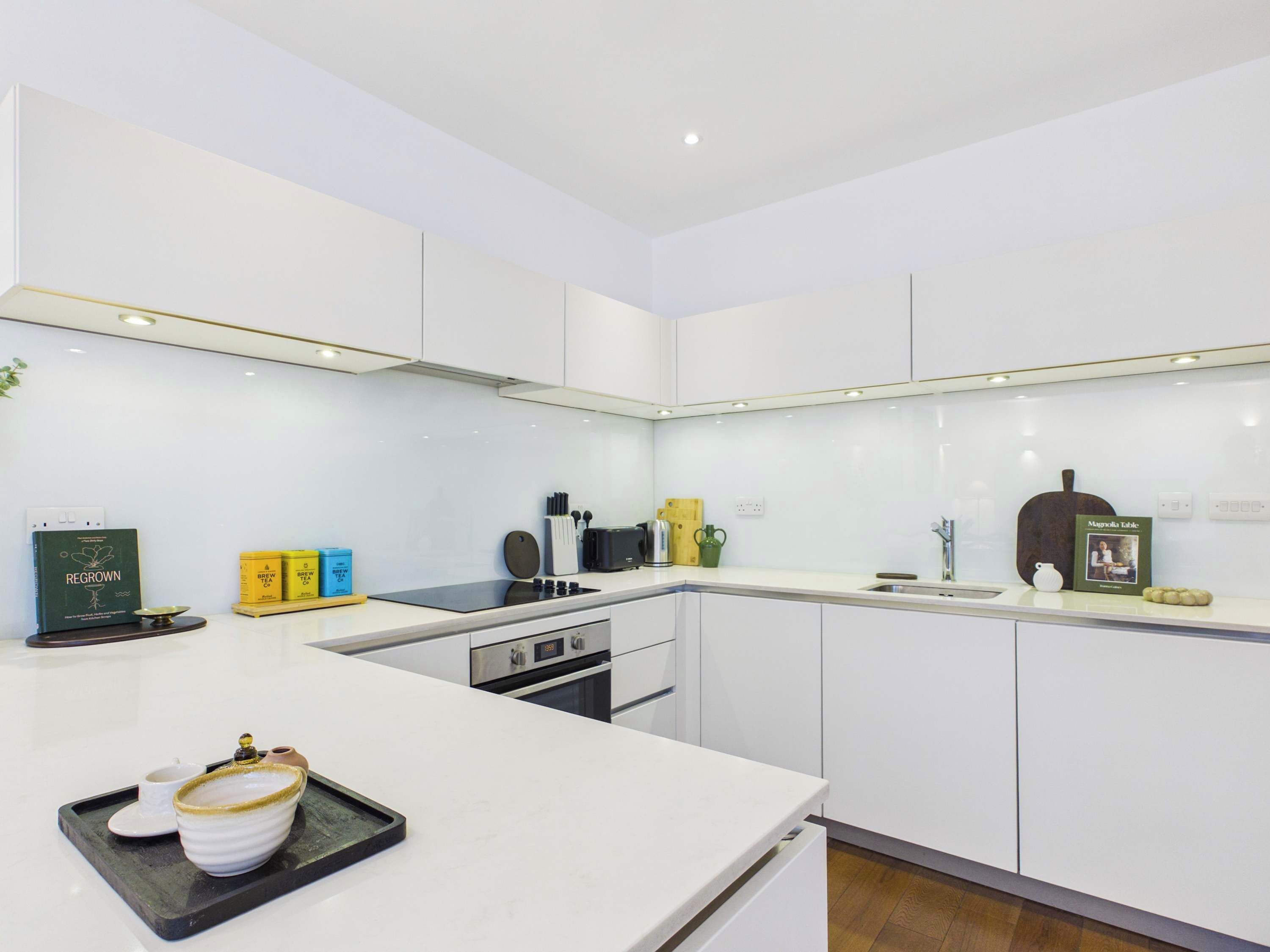Una cocina moderna con armarios blancos, una isla central y varios electrodomésticos.