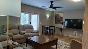 A living room with a sofa, coffee table, and a television.
