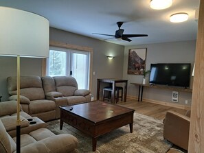 A living room with a sofa, coffee table, and a television.