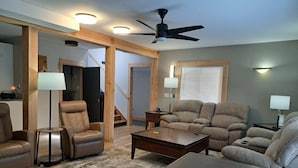 A modern living room with a ceiling fan, two sofas, a coffee table, and a checkered rug.