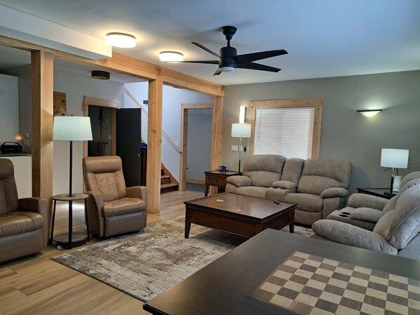 A modern living room with a ceiling fan, two sofas, a coffee table, and a checkered rug. - Bralorne Suites & Rooms (Bralorne B.C.)